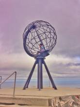 solo traveler inside a globe statue at the North Cape in Norway