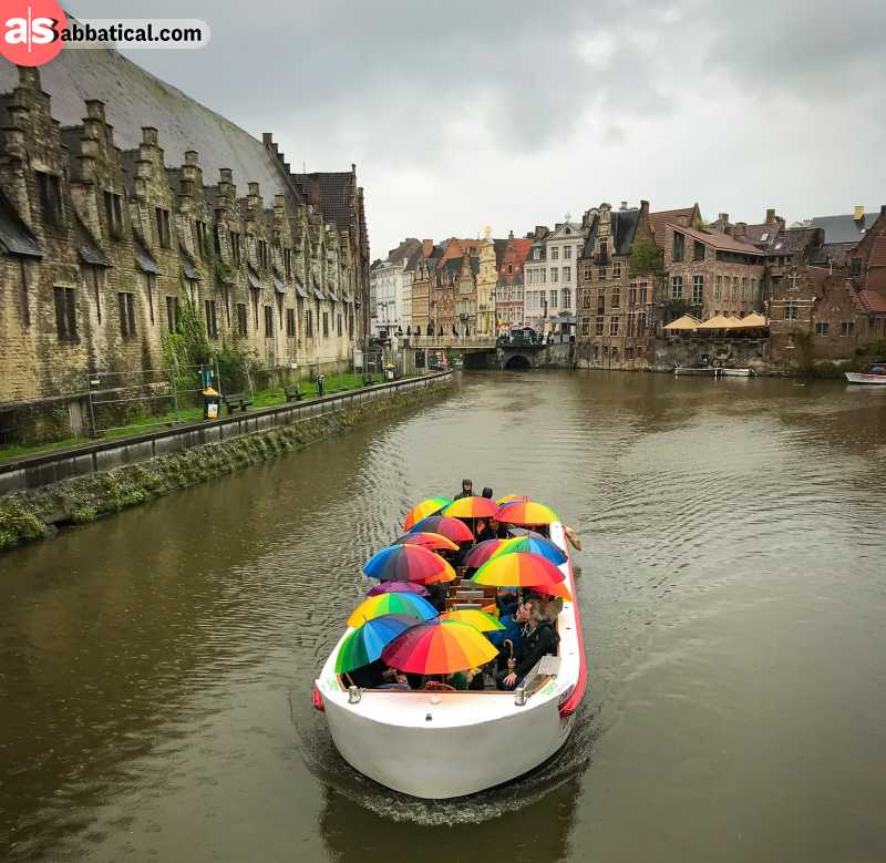 Tourists with colorful umbrellas are navigating the canals of Gent, Belgium